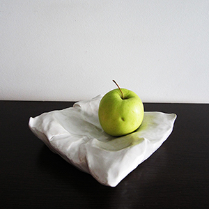 Pillow shaped decorative ceramic vase with an apple.