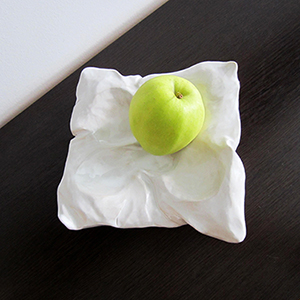 Pillow shaped decorative ceramic vase with an apple.